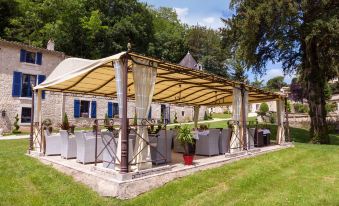an outdoor dining area with a wooden structure and a table covered in a white tablecloth at Hôtel Saint-Martin - la Maison Younan