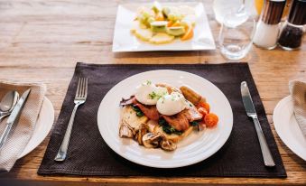 a white plate with a delicious breakfast dish and a glass of water on a wooden table at Lakestone Lodge