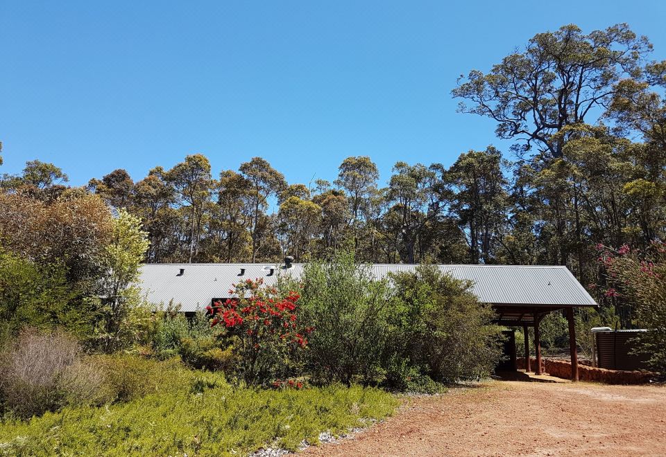 a small , rural house surrounded by trees and bushes , located in a wooded area at Jarrah Grove Forest Retreat