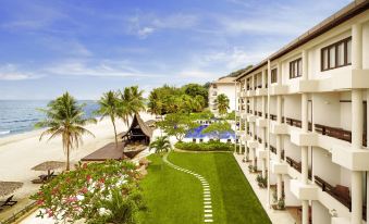 a large white building with a swimming pool in front of it , surrounded by grass and trees at Hyatt Regency Kuantan Resort