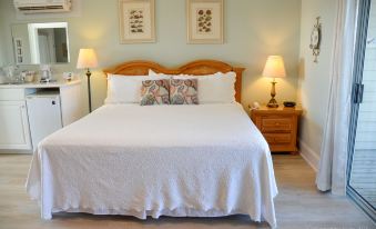 a large bed with white sheets and a wooden headboard is flanked by lamps on either side at The Sunset Inn