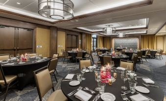 a well - lit dining room with tables set for a formal event , including silverware , wine glasses , and place settings at Cambria Hotel - Arundel Mills BWI Airport