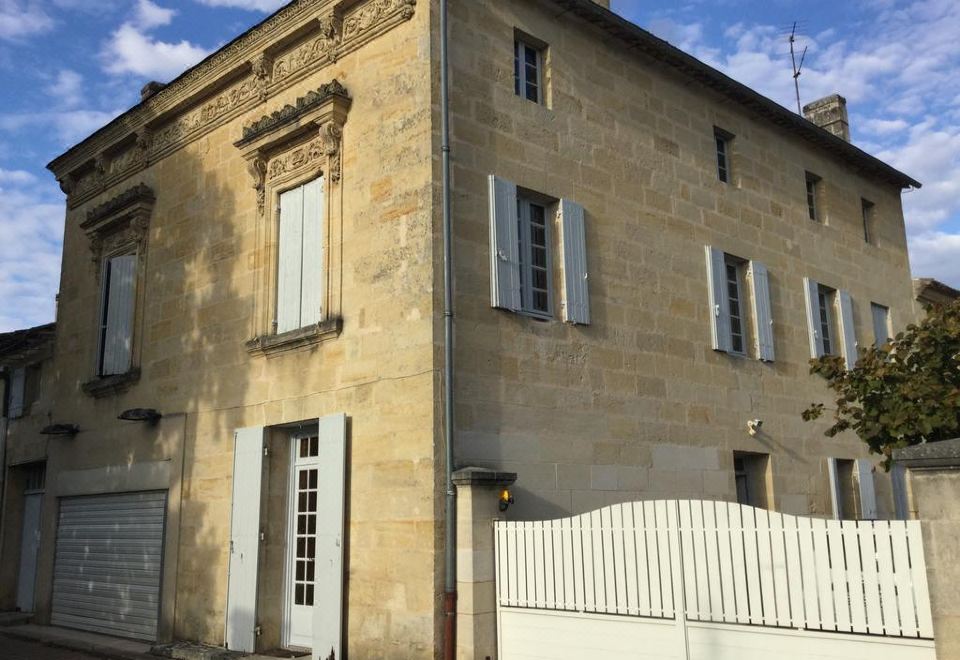 a large stone building with white shutters on the windows , situated in a residential area at Le Numero 15
