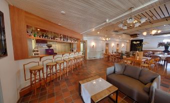 a modern bar with wooden stools , a gray couch , and various liquor bottles on shelves at Fletcher Hotel Restaurant de Gelderse Poort