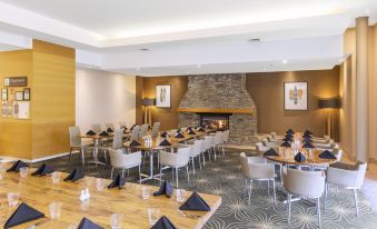 a well - lit dining room with multiple tables and chairs arranged for a large group of people at Rydges Rotorua, an EVT Hotel