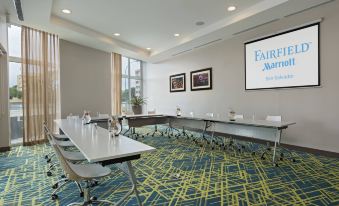 "a conference room with a long table , chairs , and a tv screen displaying the word "" prairie "" in the background" at Fairfield by Marriott San Salvador