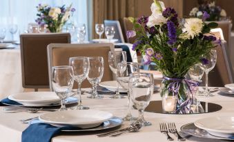 a well - decorated dining room with multiple tables set for a formal event , featuring white tablecloths , wine glasses , and flowers at Residence Inn by Marriott Boston Needham