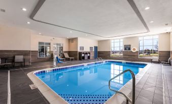 a large swimming pool with a ladder and water bottles is surrounded by windows and chairs at Four Points by Sheraton Elkhart