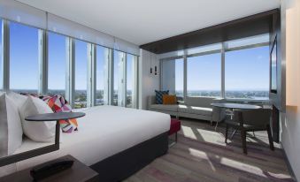 a modern hotel room with a large bed and a view of the city outside the window at Aloft Perth