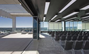a large conference room with rows of chairs arranged in front of a glass wall , providing a scenic view of the city at Aloft Perth