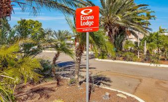 a red sign for econo lodge hotel is displayed in front of a palm tree at Econo Lodge Karratha