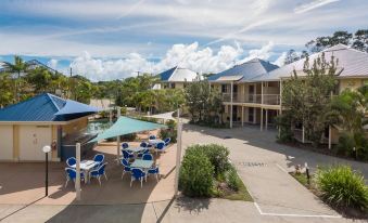 a courtyard with several chairs and tables set up for outdoor dining , surrounded by a building at Hastings Cove Holiday Apartments