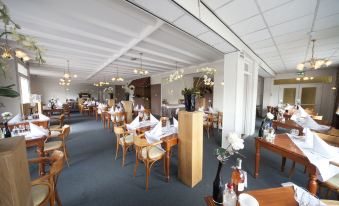 a large dining room with wooden tables and chairs , and a variety of food items on the tables at Fletcher Hotel Restaurant de Gelderse Poort