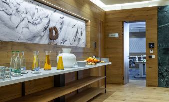 a dining area with a wooden table and chairs , as well as a kitchen counter with various food items and utensils at Radisson Blu Hotel Reussen Andermatt