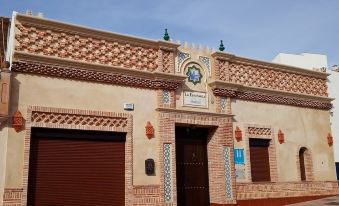 a brick building with a red door and a clock on the side , located in a city street at La Esperanza