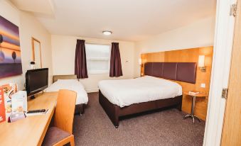 a hotel room with three beds , two of which are double beds and one is a single bed at Purple Roomz Preston South