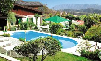 a large pool is surrounded by lush greenery and buildings , with mountains in the background at Villa Margherita