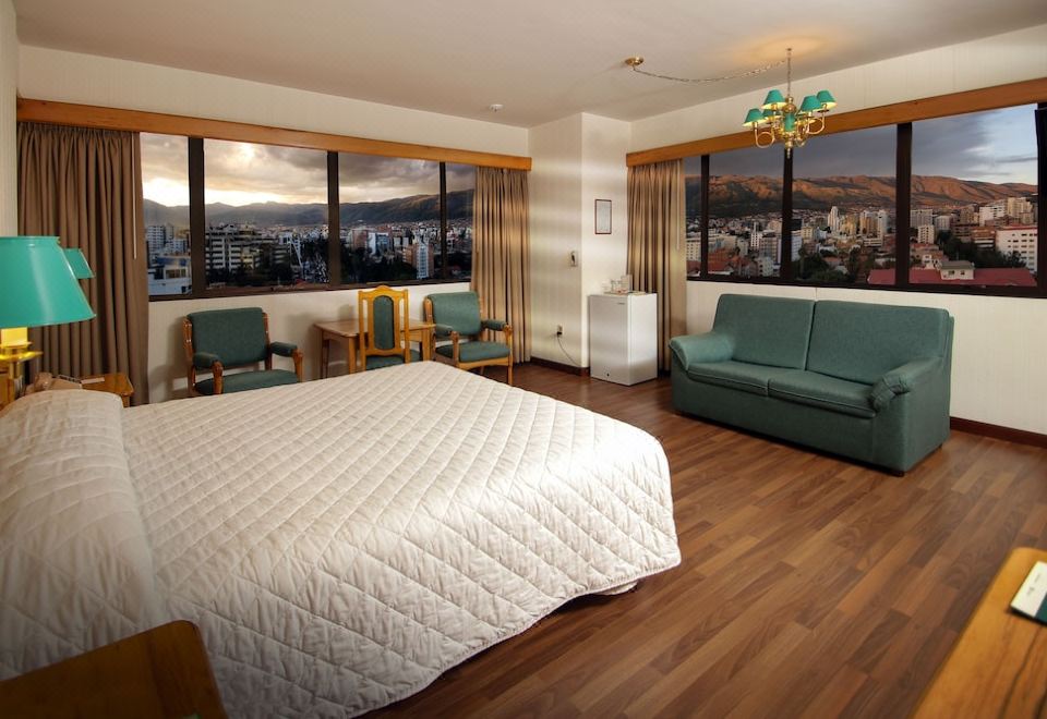 a hotel room with a bed , couch , and table , along with a view of the city outside the window at Hotel Diplomat