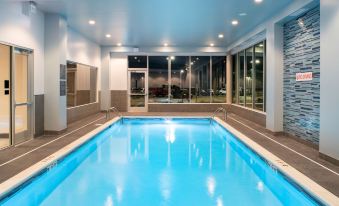 an indoor swimming pool with a blue water and white tiles , surrounded by windows that provide a view of the outside at Hyatt Place East Moline/Quad Cities
