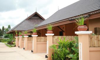 a house with a brown roof and stone walls , surrounded by plants and potted flowers at Chalicha Resort