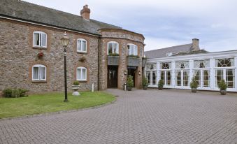 a brick building with a large front porch and multiple windows , surrounded by a grassy area at Quorn Country Hotel