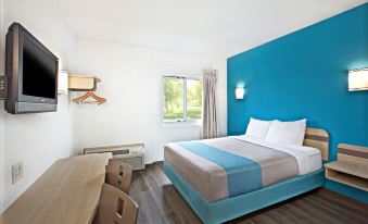 a hotel room with a blue and white color scheme , featuring a bed , a desk , and a chair at Comfort Hotel