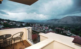 a balcony with a view of a city and mountains , with a chair on the balcony at Theasis Hotel Paramythia
