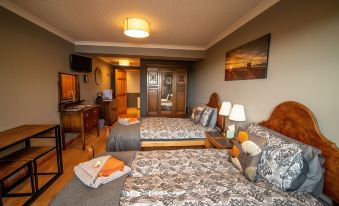 a bedroom with two beds , a desk , and a painting on the wall , all decorated in a cozy atmosphere at Burnside Cottage