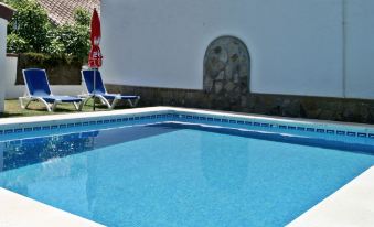 a large swimming pool with blue water is surrounded by white walls and has lounge chairs at Julian