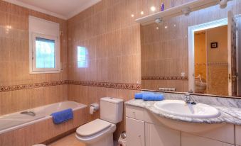 a bathroom with a toilet , sink , and bathtub , along with blue towels and toiletries on the counter at Villa Pasja