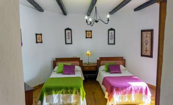 a bedroom with two twin beds , each covered in a green and purple blanket , standing under a ceiling with wooden beams at Titi