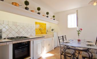 a kitchen with white cabinets , a yellow wall , and a dining table with chairs and an oven at La Fabrique