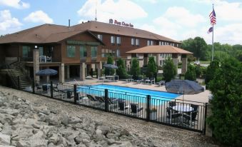 a large building with a pool and chairs is in the foreground , while an american flag is visible in the background at Best Western Park Oasis Inn