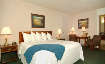a large bed with a white comforter and blue throw blanket is in the middle of a room at Best Western Plus Burley Inn Convention Center
