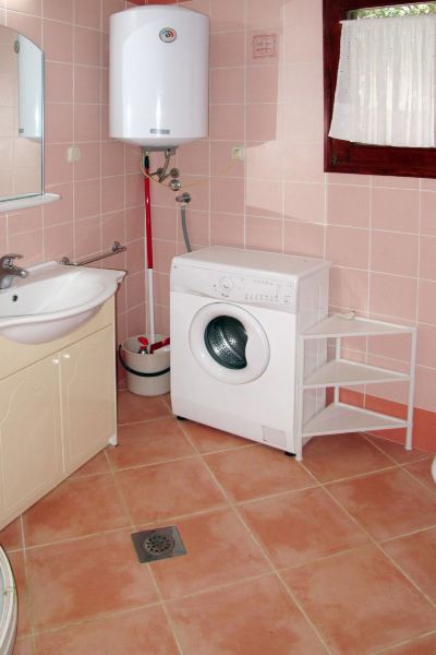 a bathroom with pink tiled walls , white tiles on the floor , and a washing machine in the corner at Ingrid