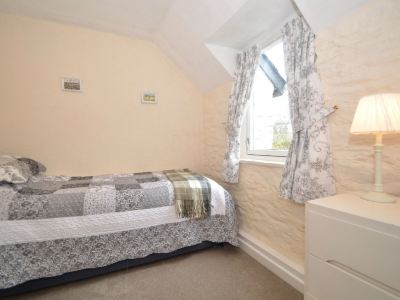 a cozy bedroom with a single bed , a window with a view , and a white dresser at Kim