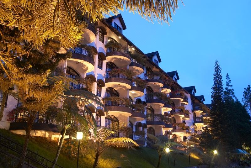 a large , multi - story building with balconies and arches is lit up at night , surrounded by palm trees at Strawberry Park Resort