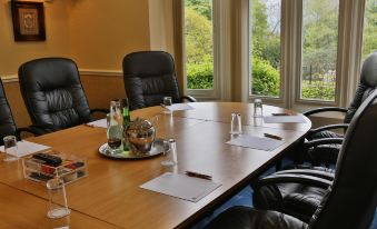 a conference room with a long wooden table , several chairs , and several bottles on the table at Higher Trapp Hotel