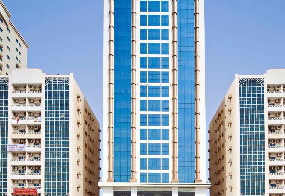 a tall , modern building with blue and white glass panels stands between two modern skyscrapers at Mangrove Hotel