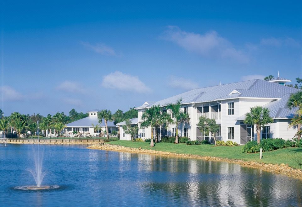 a large white building surrounded by a body of water , with a fountain in front of it at GreenLinks Golf Villas at Lely Resort