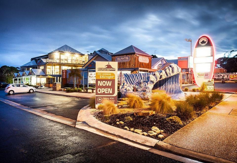 "a large sign in a town plaza with the words "" now open "" and an illustration of buildings at night" at The Island Accommodation