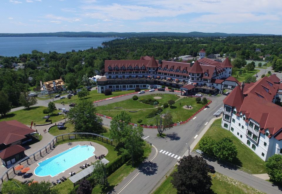 an aerial view of a large hotel with a swimming pool surrounded by trees and grass , located near a body of water at The Algonquin Resort St. Andrews by-The-Sea, Autograph Collection