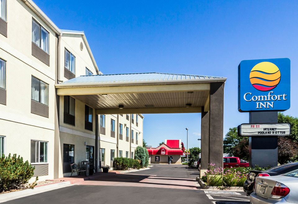 a holiday inn express hotel with its entrance and signage , under a clear blue sky at Quality Inn Denver Northeast Brighton