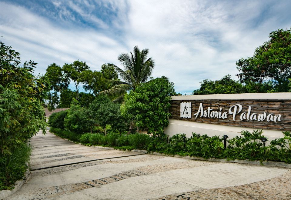 "a road leading to a building with the words "" artemis park "" written on it , surrounded by trees" at Astoria Palawan
