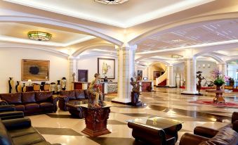 a large , well - lit hotel lobby with multiple couches and chairs arranged for guests to relax at The Rich Jogja Hotel