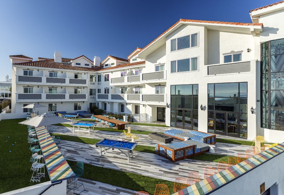 a large , well - maintained courtyard with multiple pools and umbrellas , surrounded by buildings and trees , under a clear blue sky at Hotel Hermosa