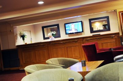 a hotel lobby with a check - in desk and a tv mounted on the wall above it at Village Hotel Liverpool