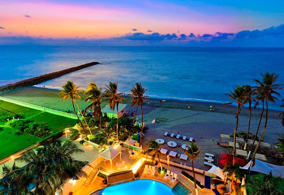 a resort with a pool surrounded by palm trees and a beach in the background at Hotel Dann Cartagena