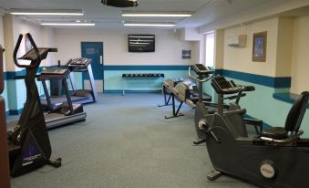 a well - equipped gym with various exercise equipment , including treadmills and stationary bikes , set against a blue and gray interior at Heights Hotel