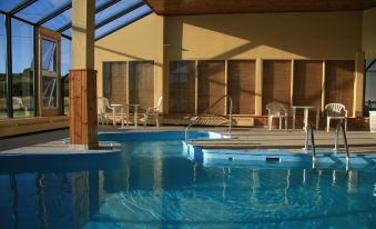 an outdoor swimming pool surrounded by lounge chairs and umbrellas , with a building in the background at Château Madelinot
